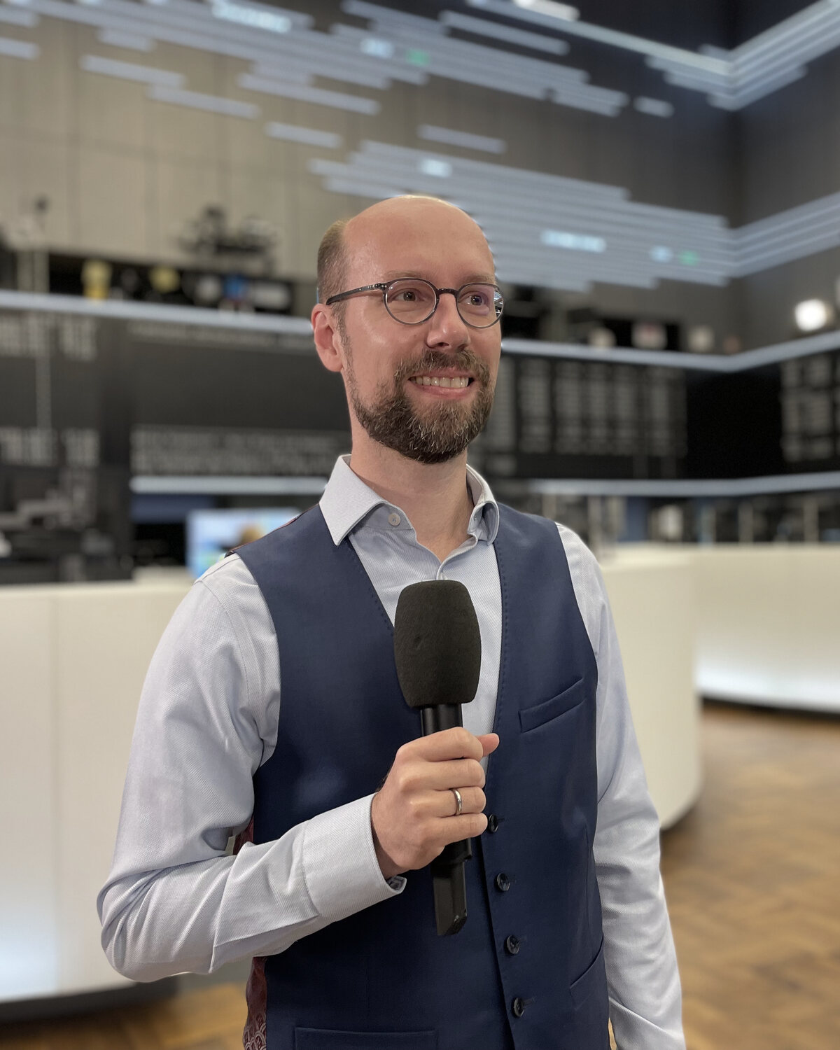Christian Schulze with a microphone on the trading floor of the Frankfurt Stock Exchange